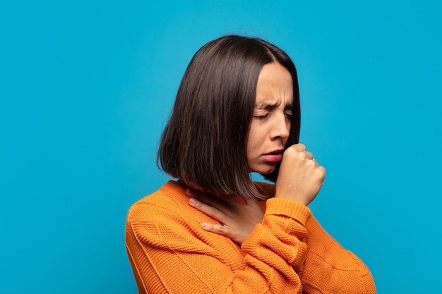 Mujer hispana que se siente enferma con dolor de garganta y síntomas de gripe, tos con la boca cubierta
