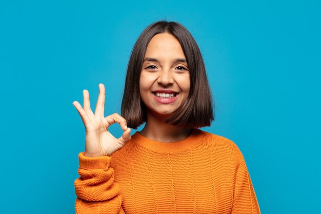 Mujer hispana que se siente feliz, relajada y satisfecha, mostrando aprobación con gesto bien, sonriendo