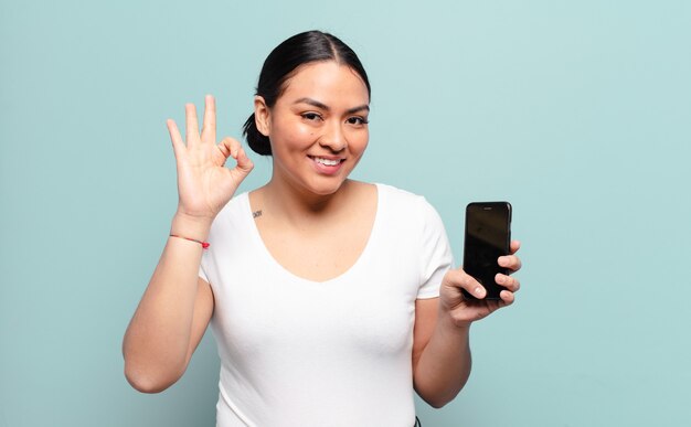 Mujer hispana que se siente feliz, relajada y satisfecha, mostrando aprobación con gesto bien, sonriendo