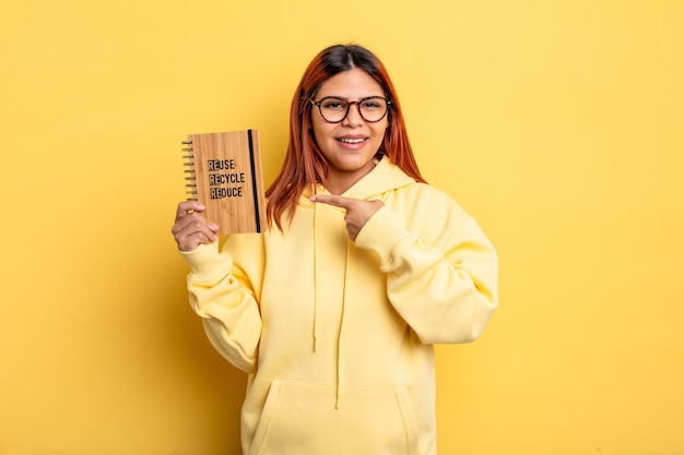 Mujer hispana sonriendo alegremente sintiéndose feliz y señalando el concepto de reciclaje lateral