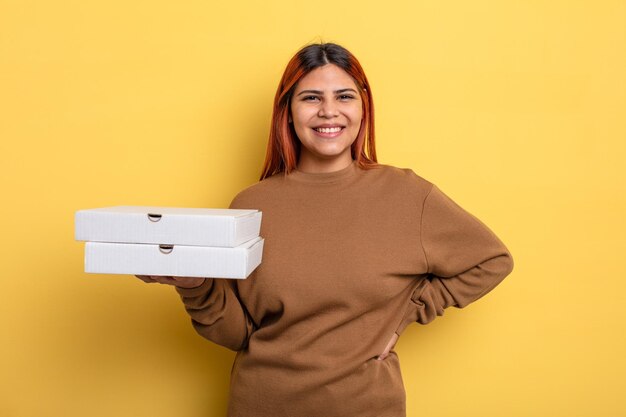 Mujer hispana sonriendo felizmente con una mano en la cadera y confiada. concepto de pizzas para llevar