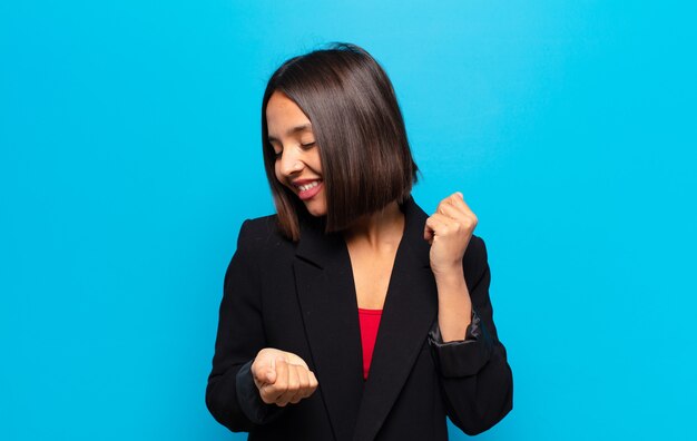 Mujer hispana sonriendo, sintiéndose despreocupada, relajada y feliz, bailando y escuchando música, divirtiéndose en una fiesta