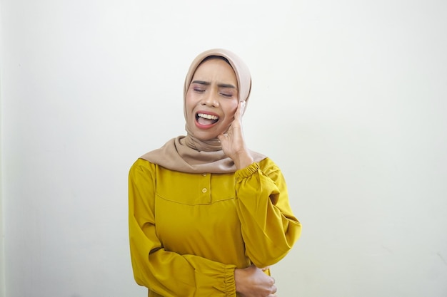 Una mujer con un hiyab amarillo llora y se lleva la mano a la boca.