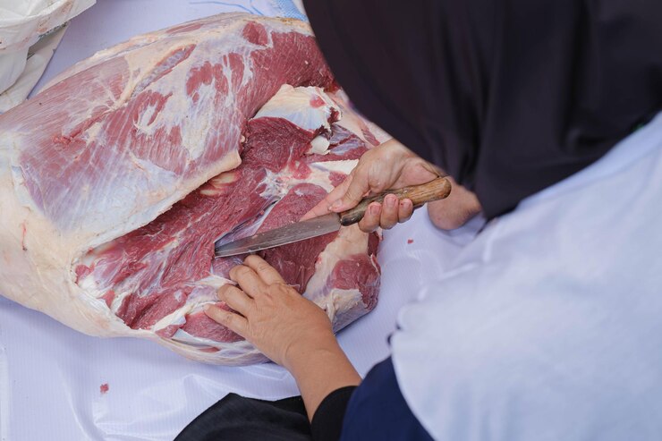 Una mujer con hiyab está cortando carne de res