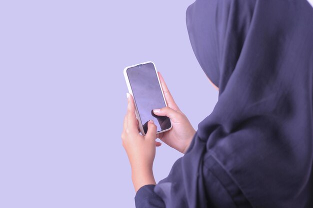 Una mujer con hiyab sostiene un teléfono con una pantalla en blanco