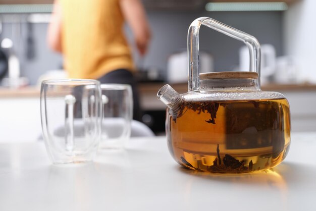 Una mujer hizo té en una tetera de vidrio closeup