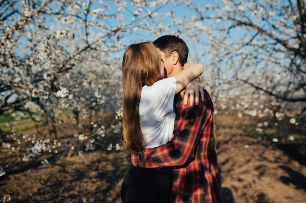 Mujer y hombre abrazándose y disfrutando de relaciones perfectas en el jardín floreciente de primavera.