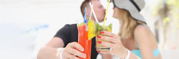 Mujer y hombre besándose y tomando cócteles refrescantes descansando en un resort de lujo