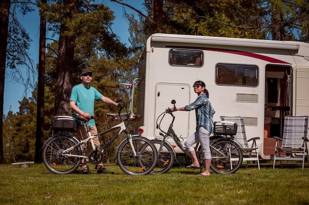 Mujer con un hombre en bicicleta eléctrica descansando en el camping. Viaje de vacaciones en familia, viaje de vacaciones en autocaravana, autocaravana, vacaciones.