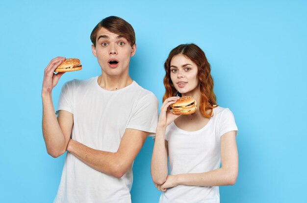 Mujer y hombre en camisetas blancas dieta de comida rápida fondo azul