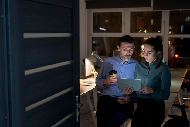 Foto mujer y hombre caucásicos trabajando juntos hasta tarde en la oficina.