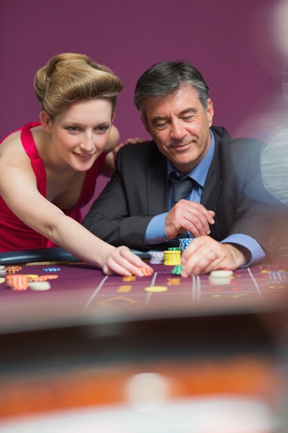 Mujer y hombre colocando apuestas en la mesa de ruleta