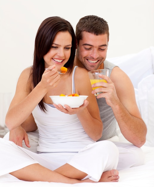 Mujer y hombre con desayuno nutritivo en la cama