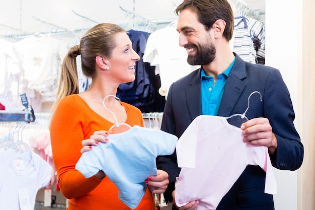 Foto mujer y hombre esperando a gemelos comprando ropa de bebé