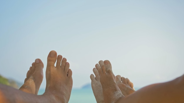 Mujer y hombre joven descalzo descansan tumbados en la playa cerca del océano