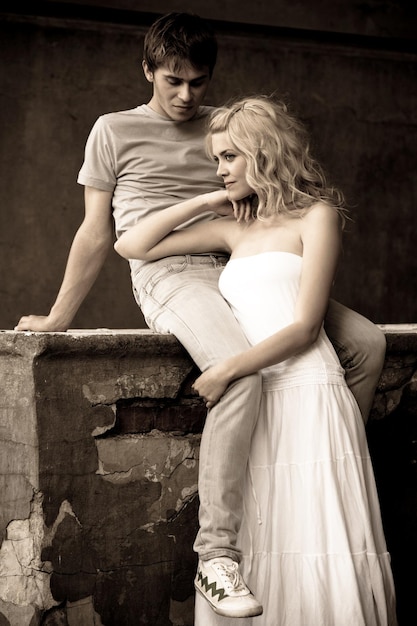 Mujer y hombre joven pareja bonita están sentados en una piedra en la acera. Concierto de relación romántica y amorosa. Foto en blanco y negro