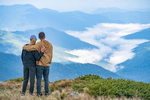 La mujer y un hombre de pie en el fondo del paisaje de montaña