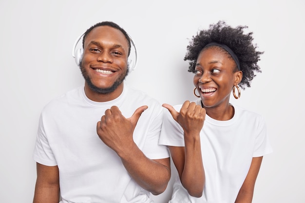 La mujer y el hombre de piel oscura feliz apuntan el uno al otro sonríen felizmente parados uno al lado del otro