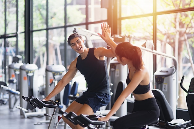 Mujer y hombre sanos con ropa deportiva corriendo entre sí dando un alto  cinco mientras entrenan en el ejercicio en el gimnasio