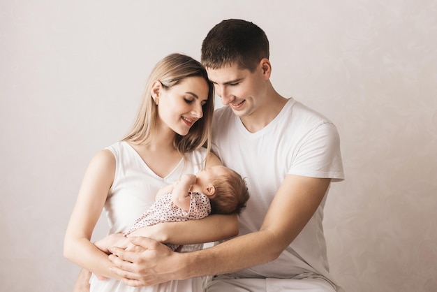 Mujer y hombre sosteniendo a un recién nacido Mamá papá y bebé Retrato de primer plano de una joven familia sonriente con un recién nacido en las manos Familia feliz sobre un fondo