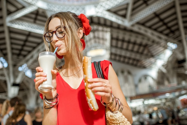 Mujer con horchata, bebida tradicional española hecha de almendras, de pie en el mercado central de la ciudad de Valencia.