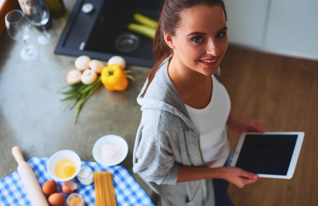 Mujer horneando en casa siguiendo la receta en una tableta