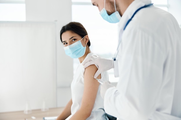 Mujer en el hospital con mascarilla médica y médico con infección epidémica de vacunación con jeringa