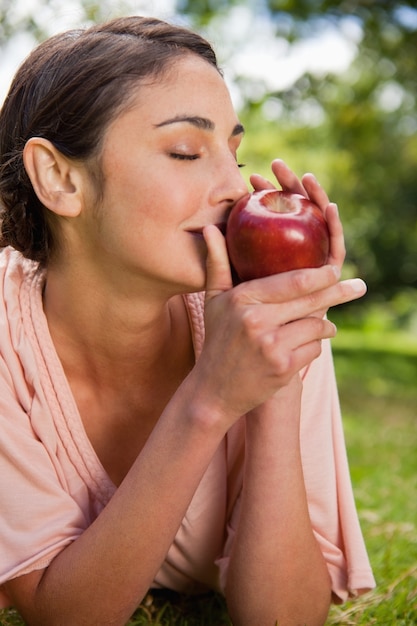 Foto la mujer huele una manzana mientras está acostado en la hierba