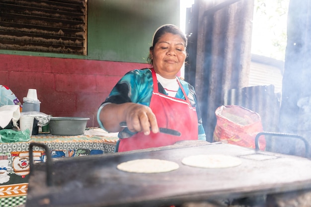 Mujer humilde de Nicaragua preparando tortillas en una plancha de metal pueblo latinoamericano