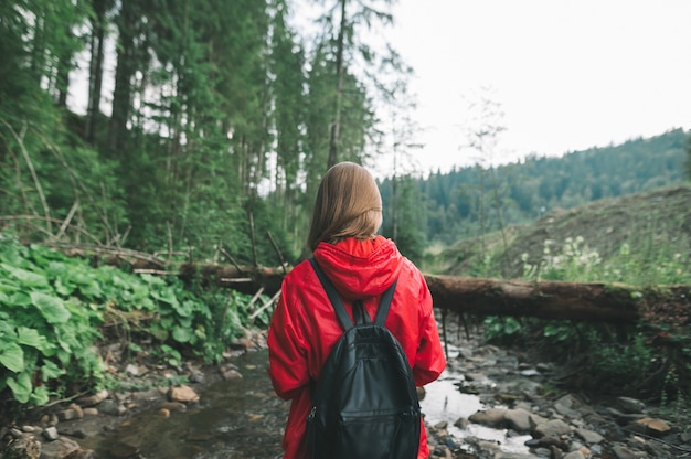 Mujer en un impermeable rojo va de excursión a la montaña