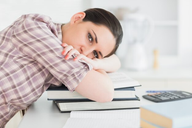 Mujer inclinando su cabeza sobre libros