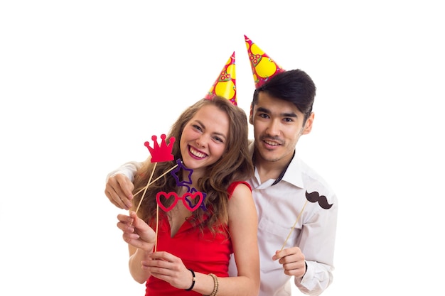 Mujer increíble joven y hombre guapo joven con sombreros de celebración con palos de tarjeta de gafas