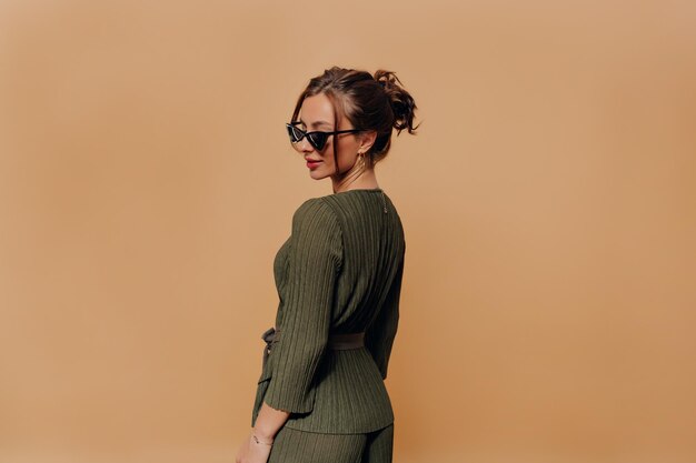 Una mujer increíble con una viga en la cabeza está vestida con un elegante traje elegante y gafas con labios rojos mirando hacia abajo y sonriendo