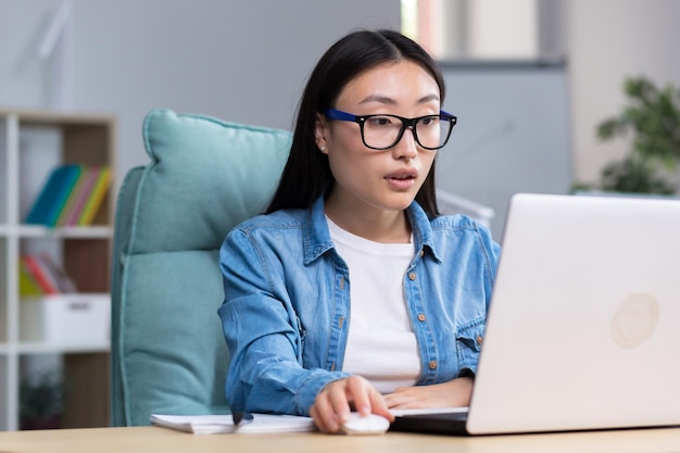 Mujer independiente asiática que trabaja con una computadora portátil en la oficina en casa mujer de negocios de forma remota con ropa informal