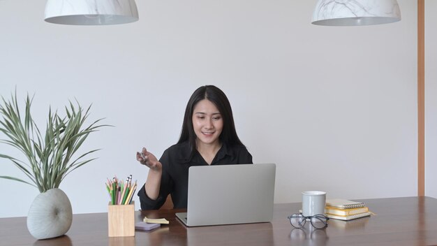 Mujer independiente bonita que tiene videoconferencia mirando la pantalla de la computadora portátil