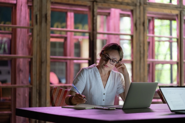 Mujer independiente enfocada sentada en el lugar de trabajo en un espacio de coworking trabajando en una computadora portátil