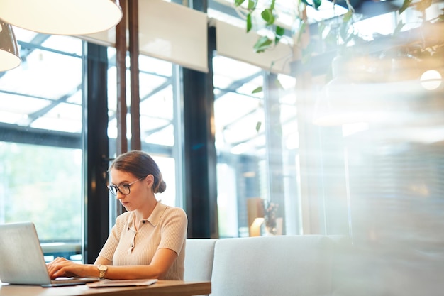 Mujer independiente escribiendo en la computadora portátil