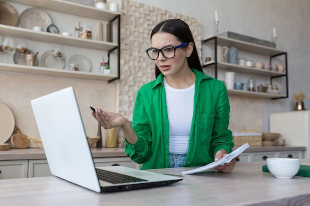 La mujer independiente milenaria positiva de la oficina doméstica trabaja en una computadora portátil desde casa por la mañana