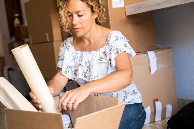 Mujer independiente organizando la mudanza de la casa poniendo objetos en una caja de cartón Mujer feliz disfrutando de actividades de ocio en el interior después de la compra de una hipoteca de préstamo Concepto de nueva propiedad y futuro