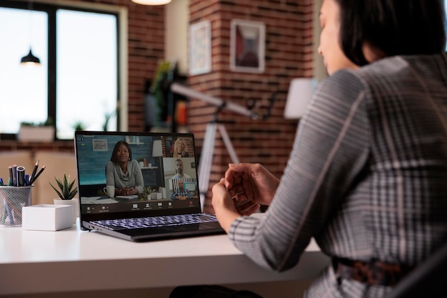 Mujer independiente reunida en videoconferencia remota con personas en una cámara web portátil, charlando en una videoconferencia virtual. Hablando en chat de teleconferencia en línea, discusión web.