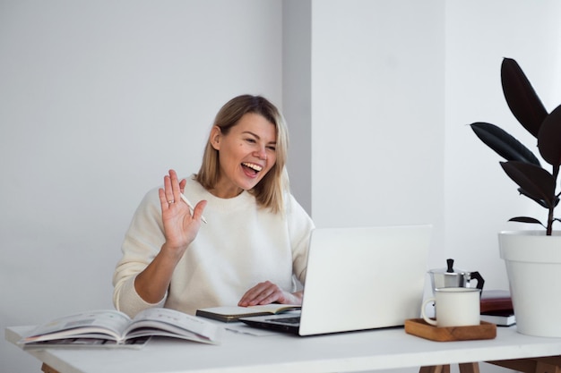 Mujer independiente trabajando en línea en la mesa usando la computadora