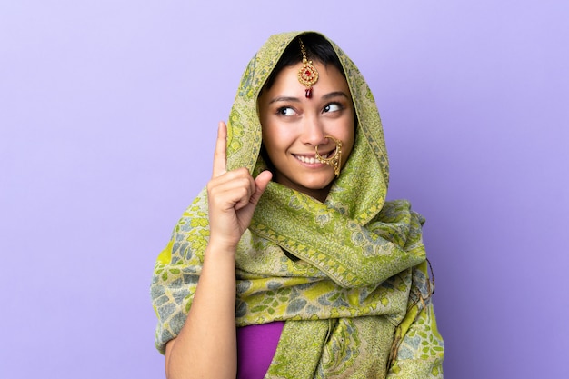 Mujer india aislada en púrpura apuntando hacia arriba una gran idea