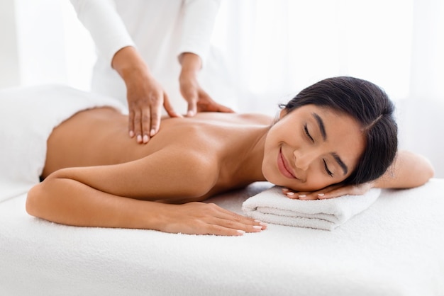 Mujer india disfrutando de un relajante masaje de espalda en un spa