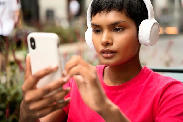 Mujer india con estilo usando teléfono móvil, comprando en línea, escuchando música en auriculares inalámbricos