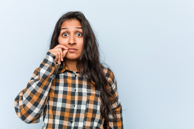 Mujer india fresca joven con los dedos en los labios que mantienen secreta.