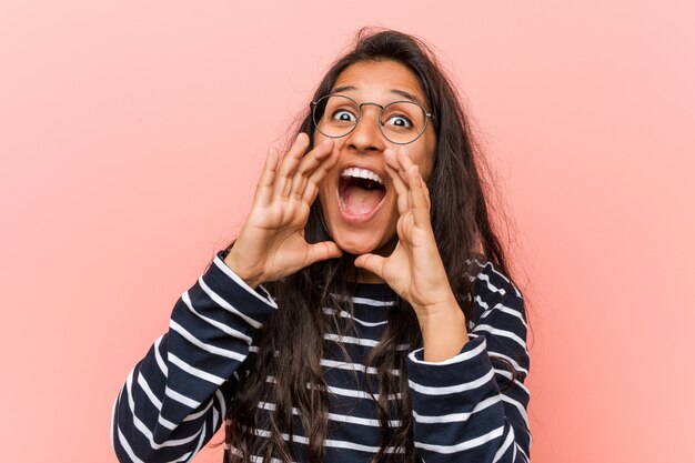 Mujer india intelectual joven que grita emocionada al frente.