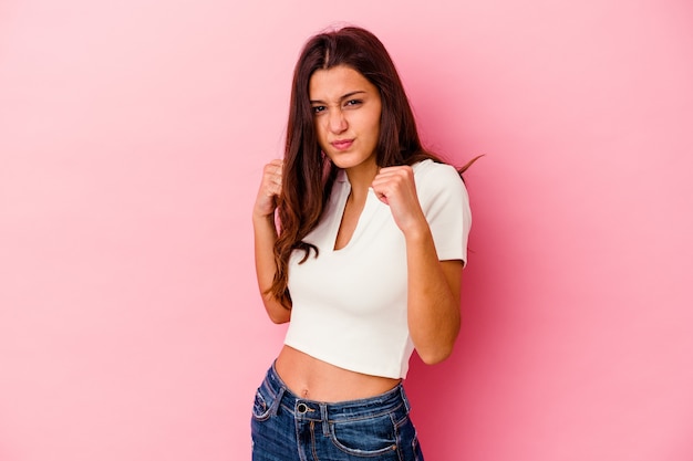 Mujer india joven aislada en la pared rosada que lanza un puñetazo, la ira, la lucha debido a una discusión, el boxeo.