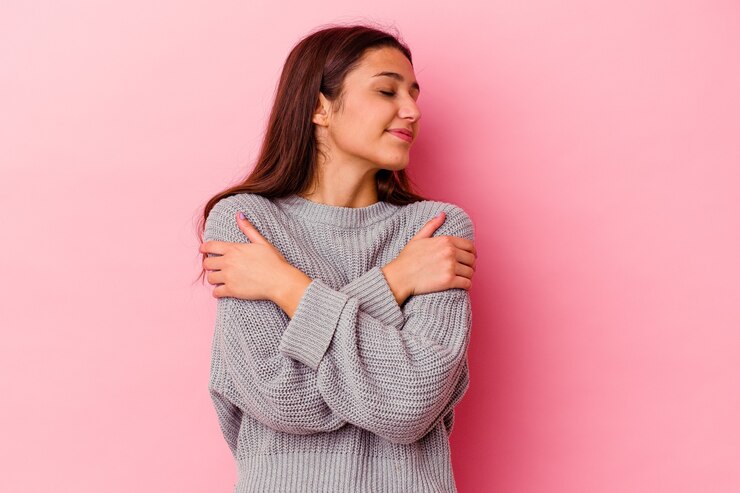 Foto mujer india joven aislada en rosa abrazos, sonriendo despreocupada y feliz.