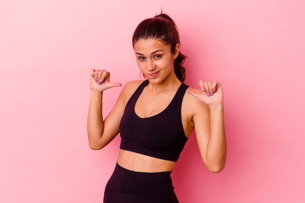 Foto la mujer india joven del deporte aislada en rosa se siente orgullosa y segura de sí misma, ejemplo a seguir.