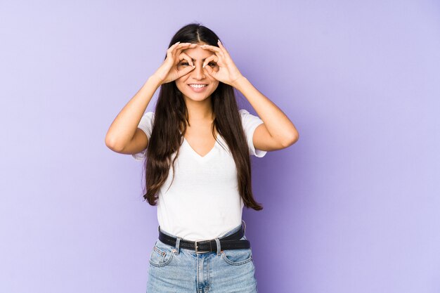 La mujer india joven en la pared púrpura excitó guardar gesto aceptable en ojo.